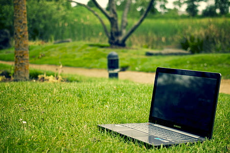 turned off black laptop computer on green grass field
