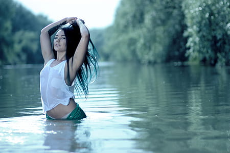 woman standing in body of water near trees
