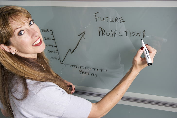 woman writing on white board using black marker
