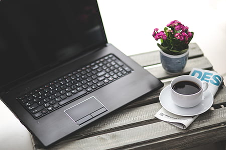 black laptop computer near white ceramic teacup