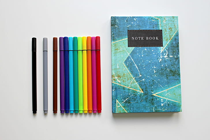 assorted-colored pens with blue and teal Note Book