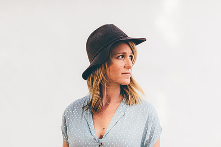 photo of woman wearing black bucket hat and beige v-neck top with white background