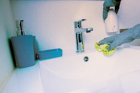 photo of person wearing gray gloves near faucet