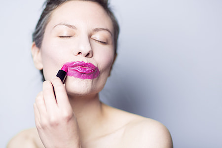 woman using pink lipstick