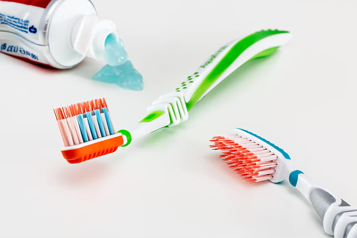 two green and gray toothbrushes on white surface