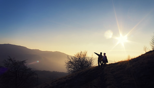 silhouette of two person standing on mountain during daytime