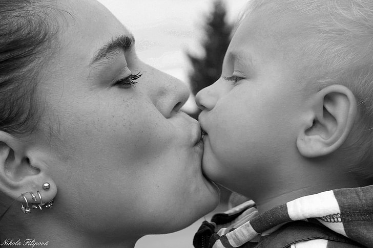 photo of woman kissing her son
