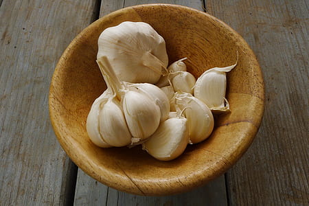 white garlic on brown wooden bowl