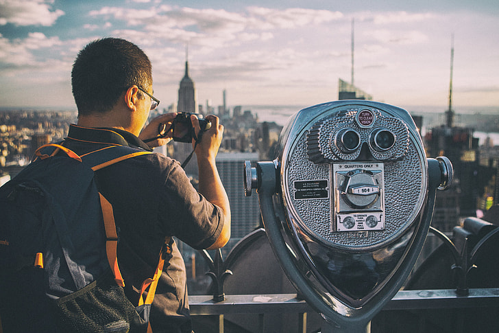 A tourist takes a picture with his camera on the Top Of The Rock observation deck at the famous Rockefeller Center, Manhattan, New York City