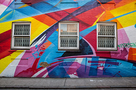 Wide angle shot of a brick building in East London that is covered in brightly coloured street art. Image captured with a Canon DSLR