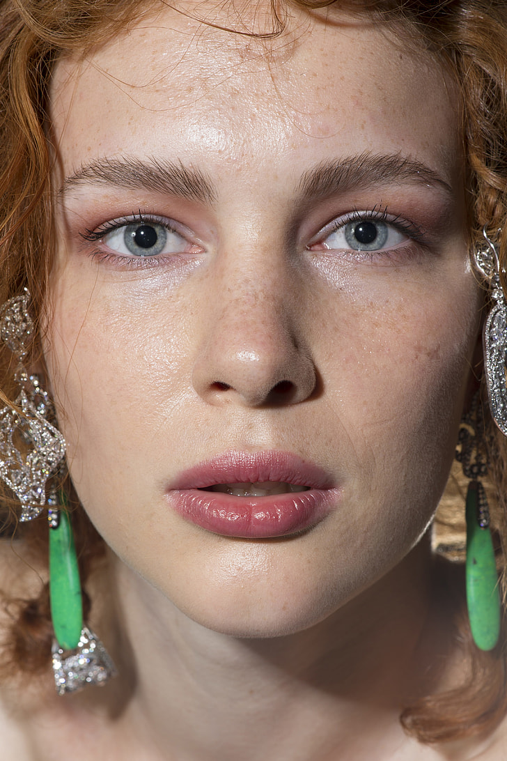 close view of woman wearing green gem earrings