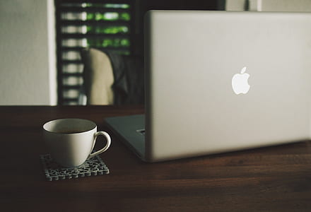 MacBook Pro on table near white ceramic teacup