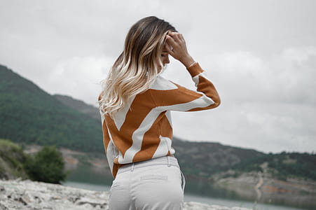 woman wearing brown and white long-sleeved top and white pants