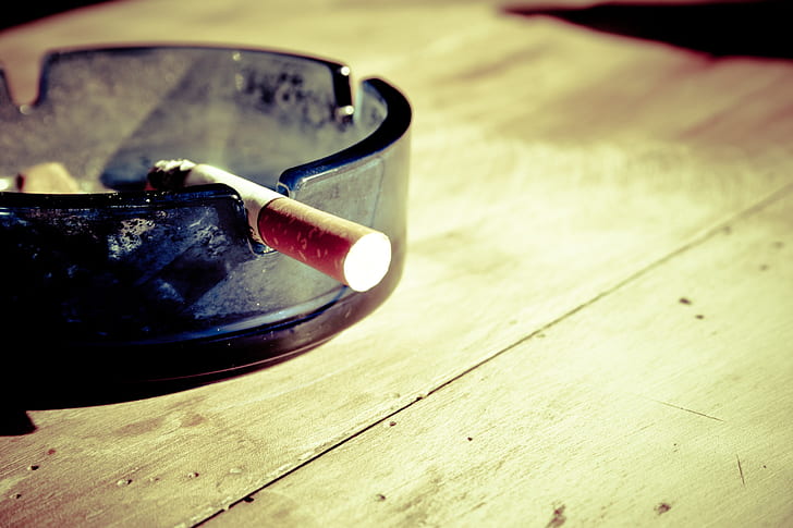 single cigarette on glass ashtray