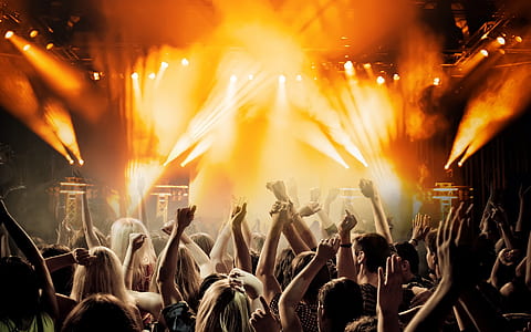 people raising hands infront of stage with band playing