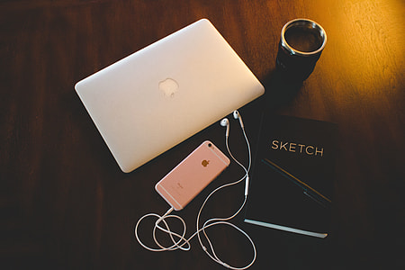 Laptop, sketchbook and iPhone mobile smartphone on a desk