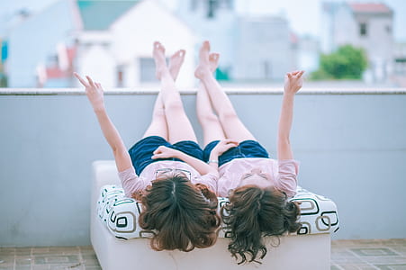 two girl's wearing same shirts and shorts lying down on roof top