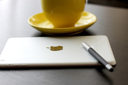 silver iPad near yellow ceramic teacup