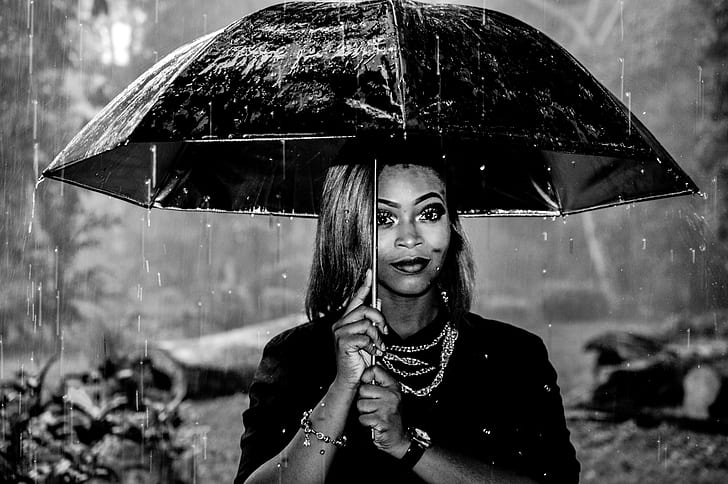 grayscale shallow focus photography of woman holding umbrella under rain
