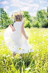 girl in white dress standing on flower field