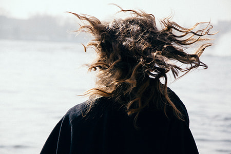 woman standing, wearing black jacket beside of seashore