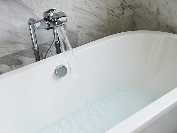 white ceramic bath tub with stainless steel faucet during daytime