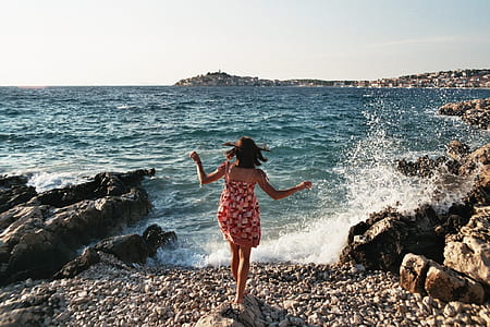 woman wearing red spaghetti strap dress in front of blue body of water