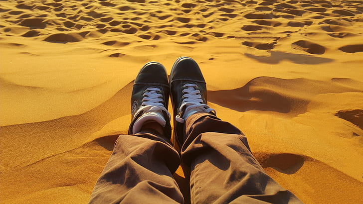 person sitting on sand dunes