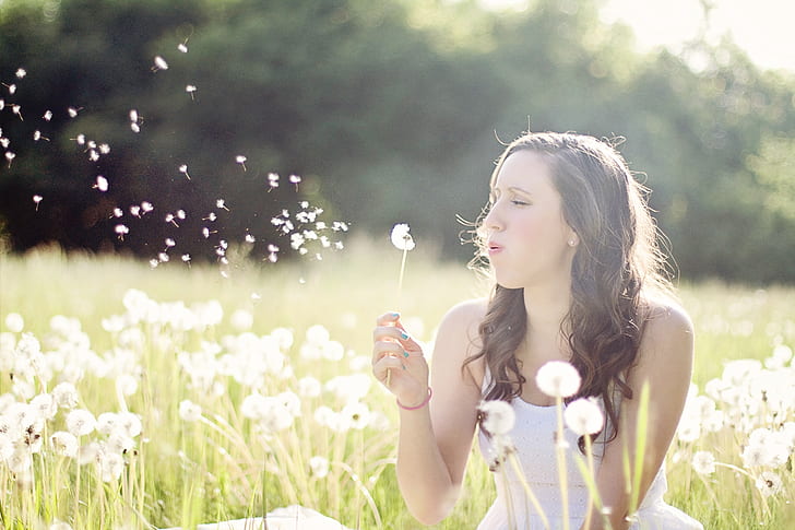woman wearing white top on dandelion grass field during daytime