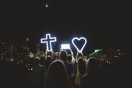 selective focus photography of people holding cross and heart lights