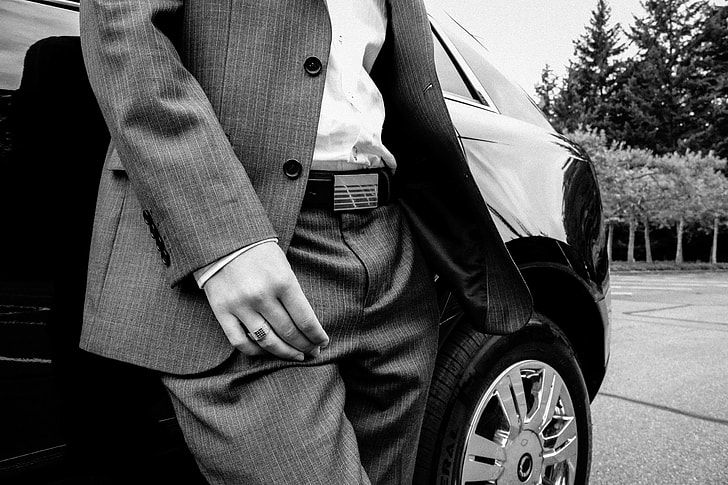 person in pinstripe suit jacket and dress pants standing beside car
