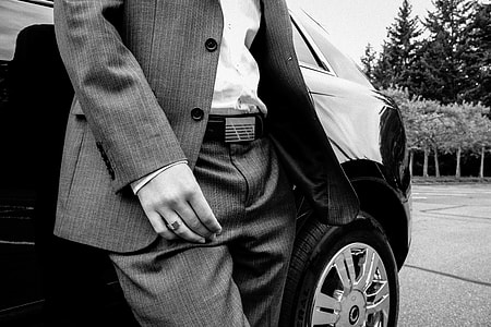person in pinstripe suit jacket and dress pants standing beside car