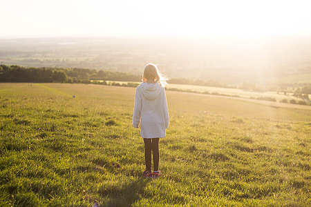 woman standing in green fields during day time