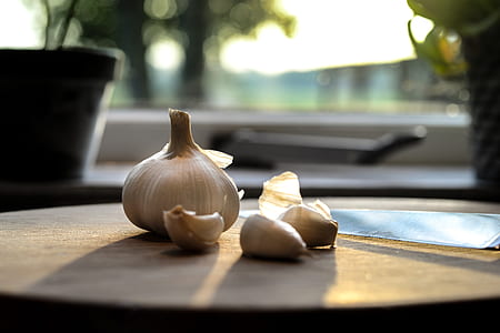 close u p photograph of garlic on brown chopping board