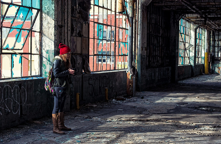 woman wearing red knit cap inside abandoned building near window