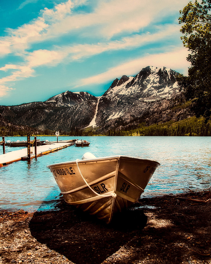 brown canoe boat against body of water and mountain