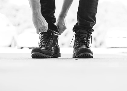 gray scale photo of person wearing jeans and boots