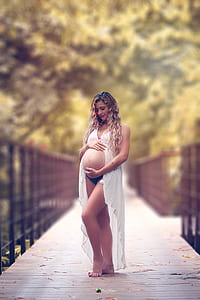 pregnant woman holding her tummy standing on bridge
