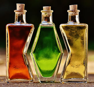 three clear glass bottles with yellow, green, and red liquids