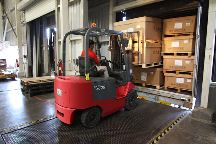 man riding on red and gray forklift