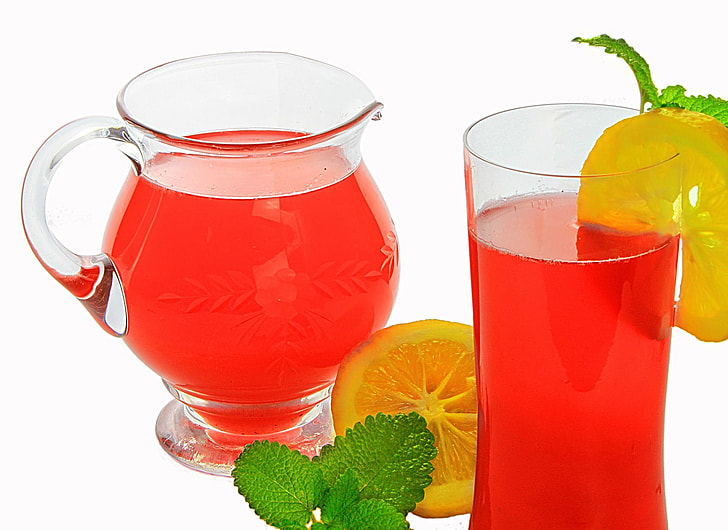 red juice in pitcher and glass with slice of lemon