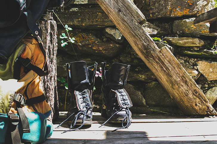 Royalty-Free photo: Pair of black leather boots beside yellow hiking backpack - PickPik
