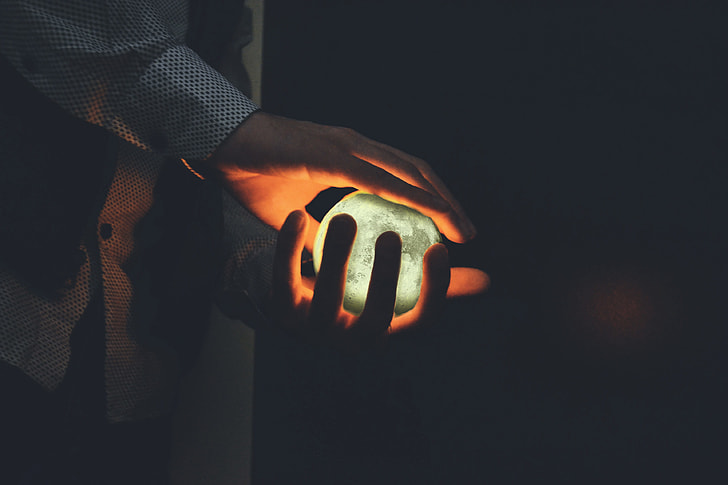 Closeup shot of a man’s hands holding a glowing orb