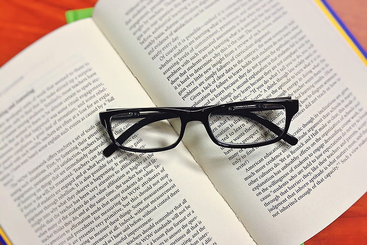 black framed eyeglasses on open book