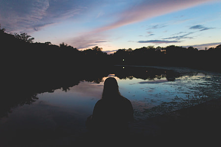silhouette of person facing body of water