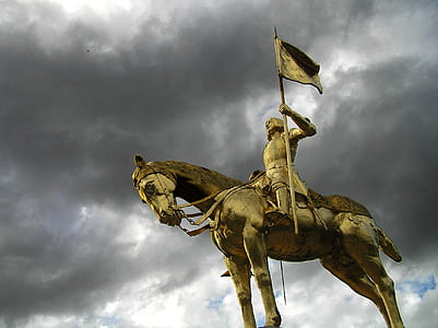 man riding on horse statue under gray clouds