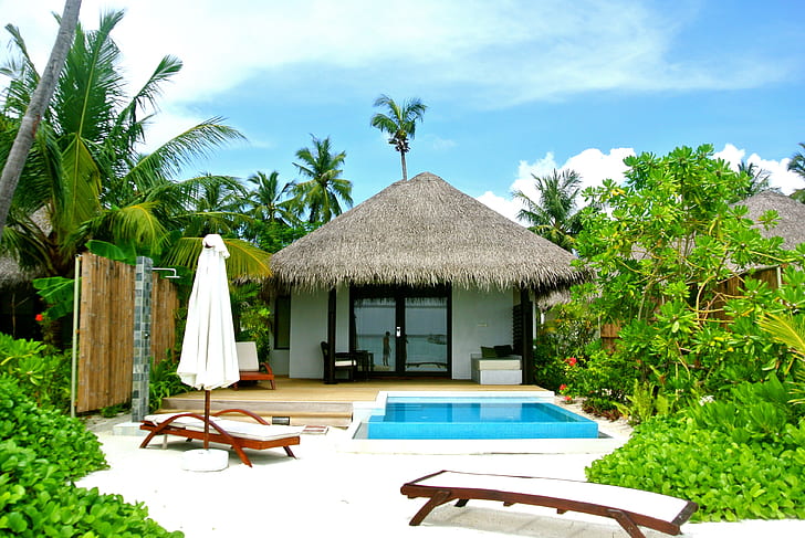landscape photo of two house behind swimming pool with two loungers
