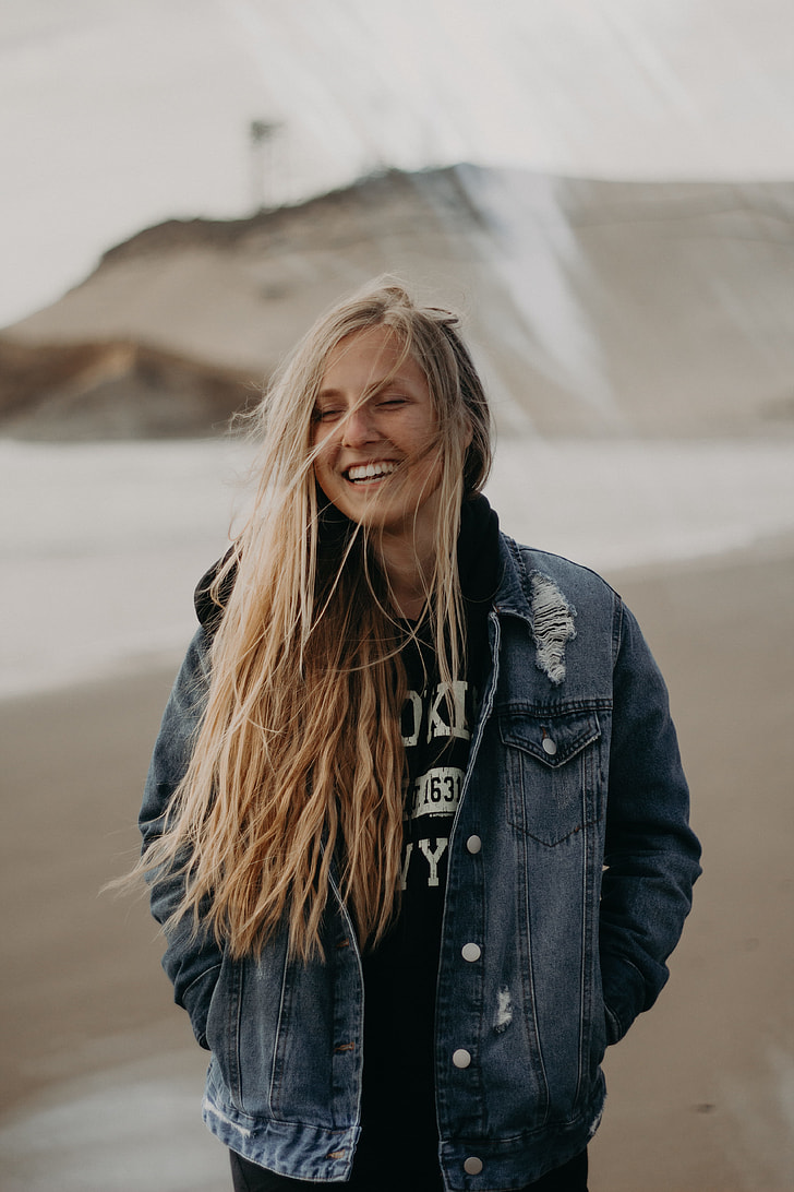 woman in blue denim jacket smiling while her hands in pocket
