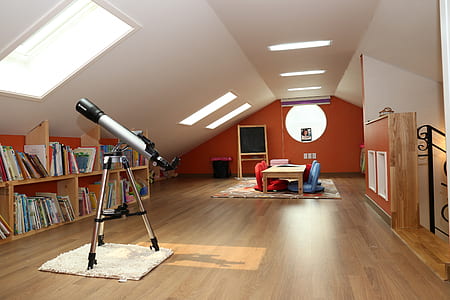 gray telescope near brown wooden book shelf
