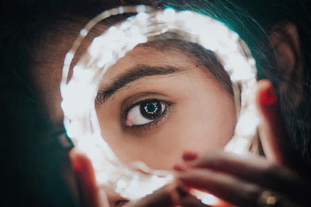 selective photography of woman's eye on center of white string light